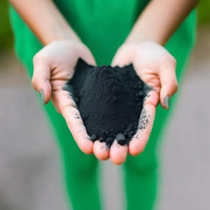 activated charcoal in hand of a girl with green background